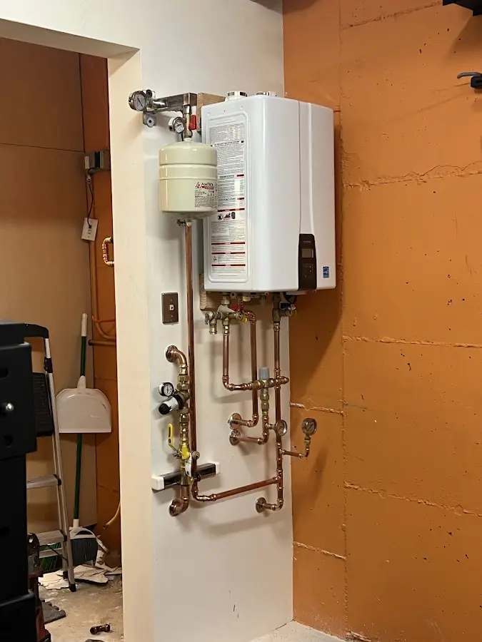 Plumbing technician inspecting water heater connections in Oneida